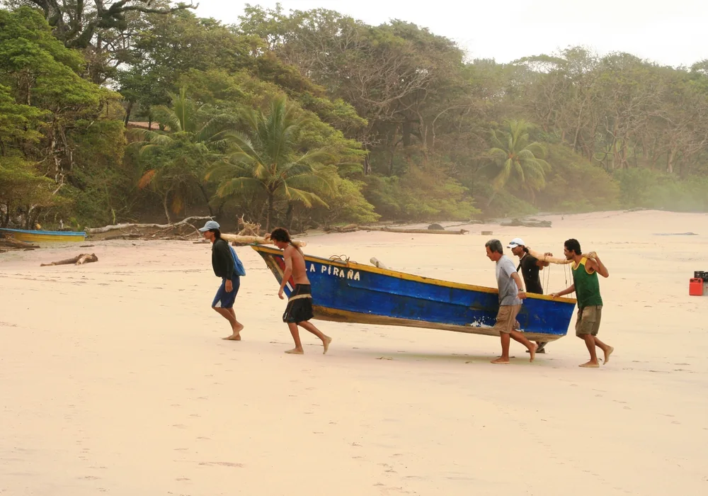 Fishermen hauling a boat up the sand at Playa Nosara