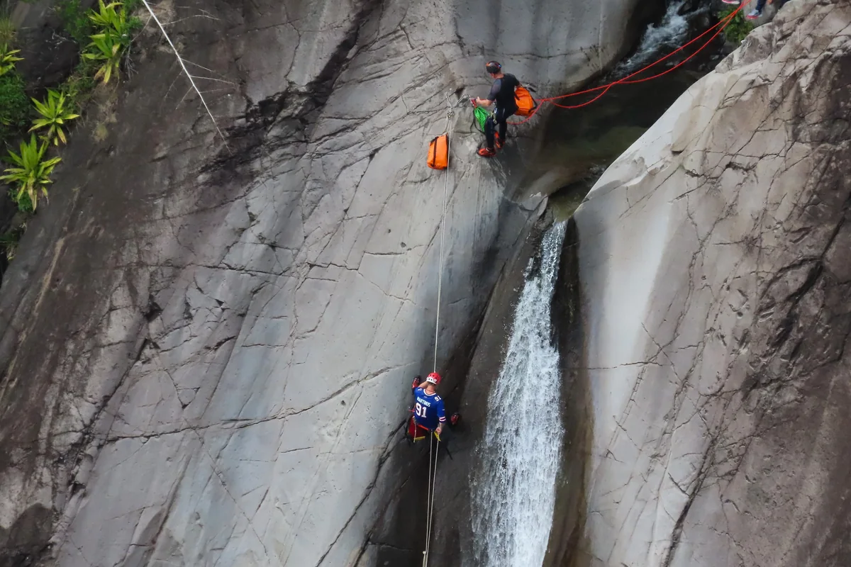 Canyoners rappelling down a waterfall cliff