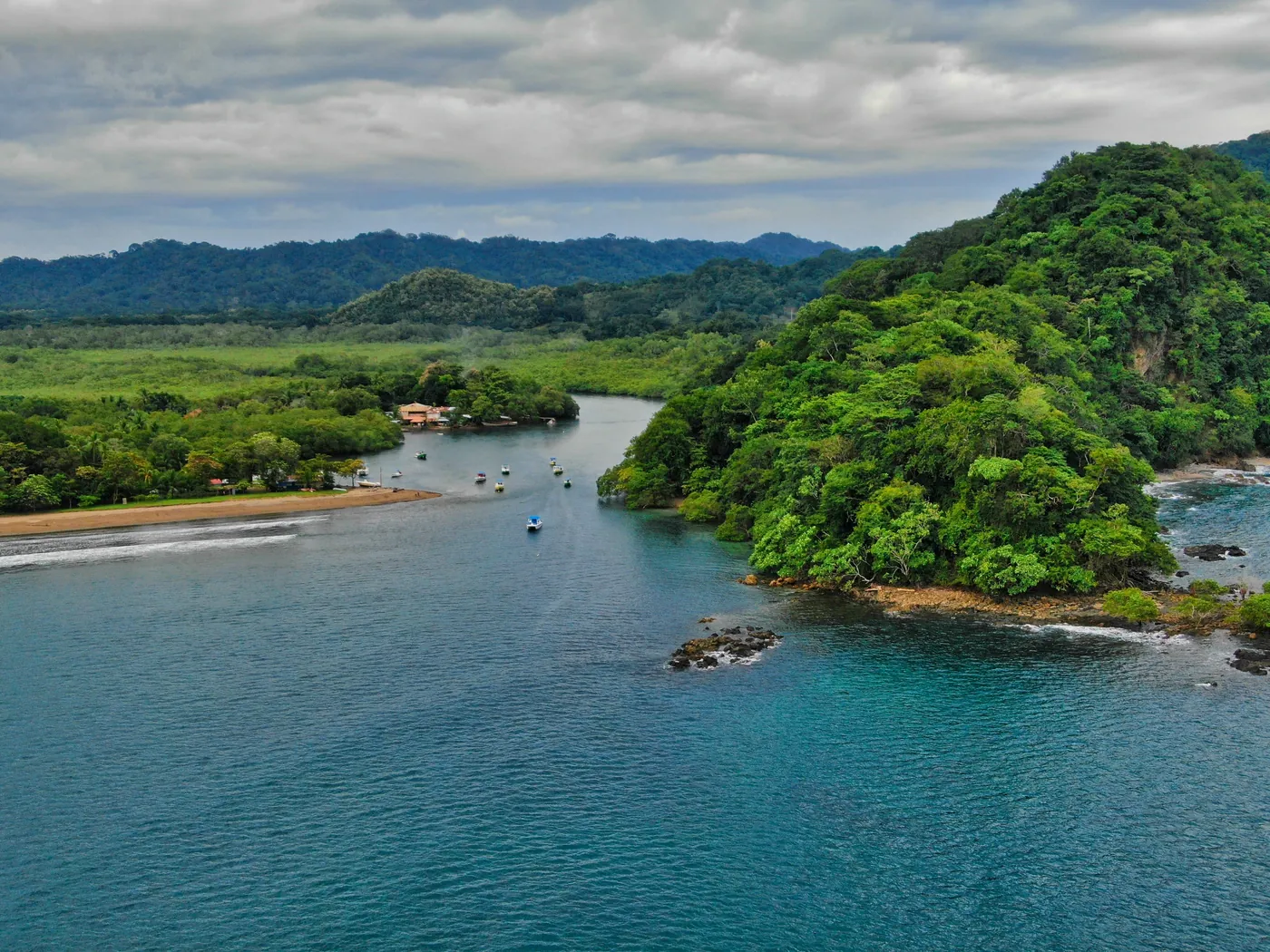 Aerial view of fishing boats anchored in a green, forested bay at Bahía Garza